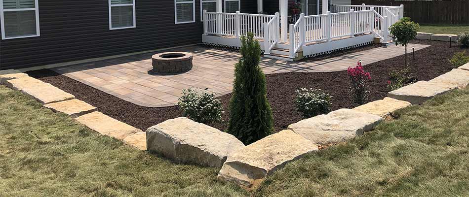 Custom patio area with fire pit, retaining wall, and mulch installation in Edwardsville, IL.