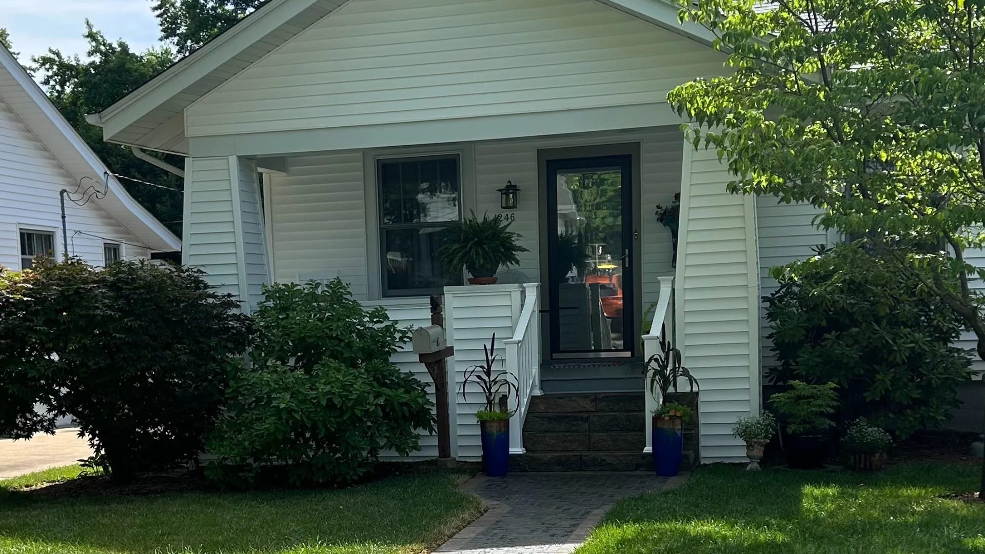 Charming white house with a landscaped front yard and a welcoming garden path leading to the entrance.