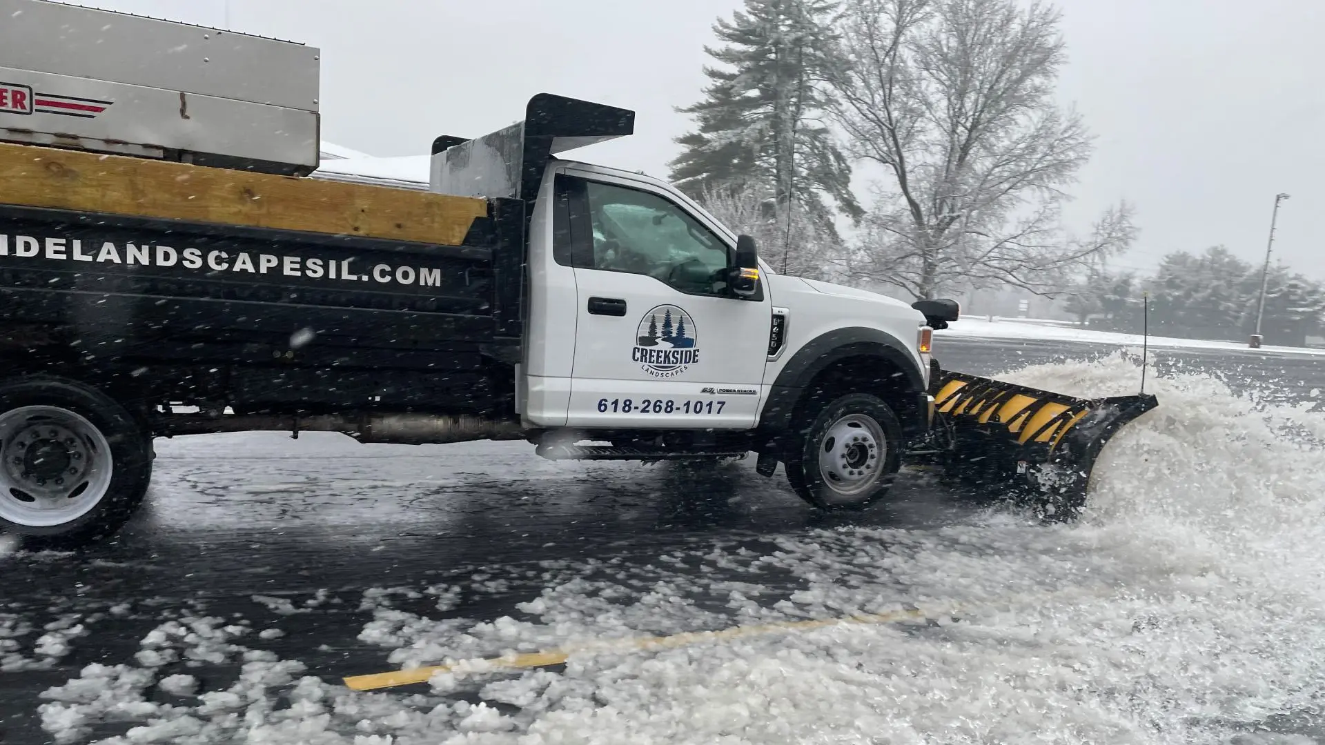 Creekside plowing truck in commercial lot during snowfall in Edwardsville, IL.