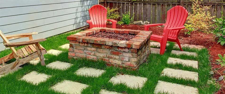 Custom red brick fire pit on a lawn in Glen Carbon, IL.