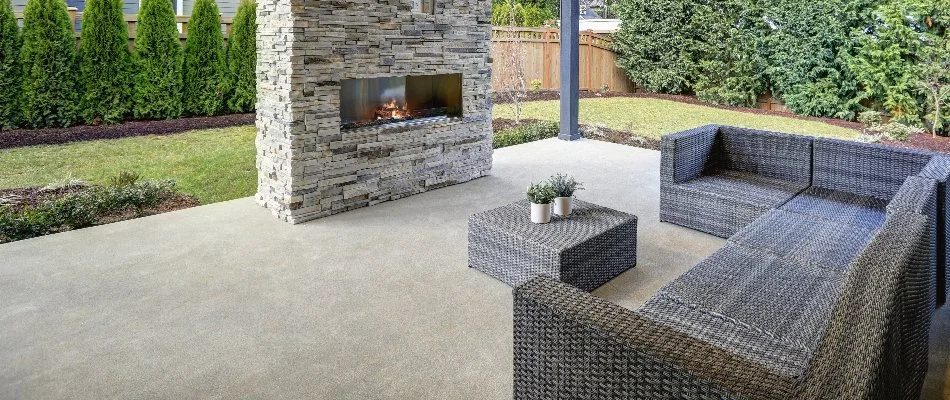 Plain concrete patio in Edwardsville, IL, with an outdoor fireplace and a couch.