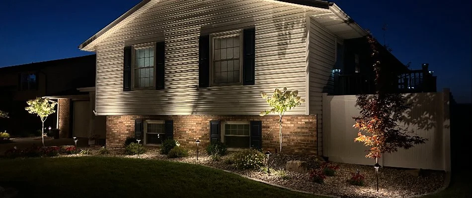 Beautifully illuminated home exterior at night showcasing landscaped garden and architectural features