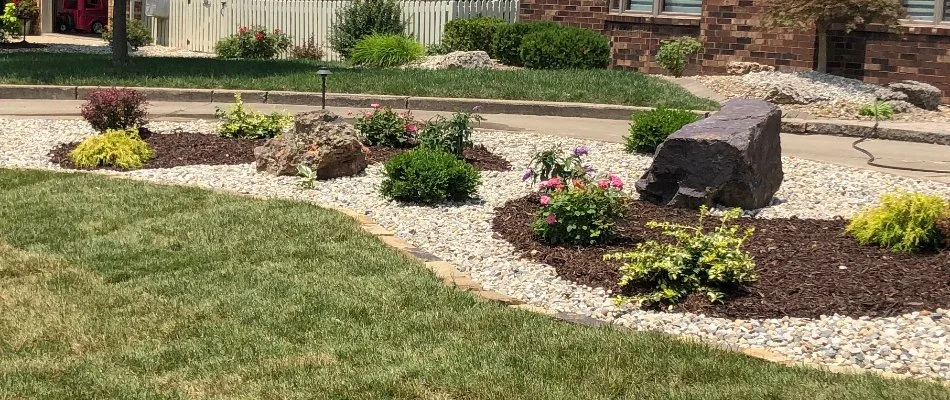 Landscape bed in Macoupin County, IL, with rocks, mulch, and flowers.