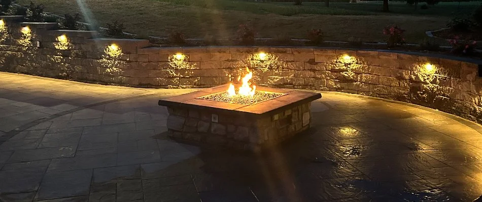 A retaining wall with lighting in O'Fallen, IL, a patio, and fire pit.