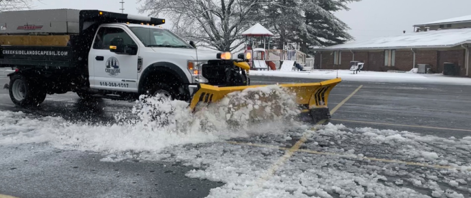 Snow plow truck clearing commercial parking lot in Edwardsville, IL.